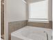 Bright and clean bathroom featuring a soaking tub beneath a window with modern neutral finishes at 211 Aspen Valley Ln, Dallas, GA 30157