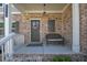 Inviting porch with brick accents, a cozy bench, and a decorated front door at 211 Aspen Valley Ln, Dallas, GA 30157