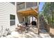 Covered outdoor patio with comfortable seating area, stairs to deck, and a view of a wooded backyard at 211 Aspen Valley Ln, Dallas, GA 30157