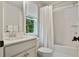 Bright bathroom features a white vanity with marble countertop, window, and shower with a white curtain at 4383 Capstone Ne Ct, Roswell, GA 30075