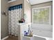 Relaxing bathtub with a window and a shower featuring decorative tile and modern fixtures at 995 Chimney Trace Way, Lawrenceville, GA 30045