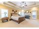 Bedroom showcasing a tray ceiling, neutral carpet, fireplace, and wooden furniture; access to outside through door at 270 Annelise Park Dr, Fayetteville, GA 30214