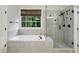 Bright bathroom with a soaking tub under the window, and a tiled glass shower at 3250 Seven Oaks Dr, Cumming, GA 30041