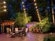 Evening view of a back deck featuring lights, lush greenery, grilling area and multiple seating areas at 605 Ga 120 Hwy, Roswell, GA 30075