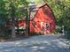 Exterior view of red barn with white doors and stone trim, set amid trees and gravel driveway at 605 Ga 120 Hwy, Roswell, GA 30075