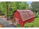 Exterior shot of a red barn with a metal roof, surrounded by lush greenery and trees at 605 Ga 120 Hwy, Roswell, GA 30075