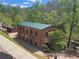 An exterior shot of the Roswell Mill, showing its brick facade, updated green roof and location near the forest at 605 Ga 120 Hwy, Roswell, GA 30075
