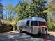 Airstream camper parked in a serene, wooded setting with a charming wooden cabin in the background at 605 Ga 120 Hwy, Roswell, GA 30075