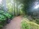Wooded walking path with lush landscaping and peaceful backyard pond at 605 Ga 120 Hwy, Roswell, GA 30075