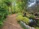 Scenic wooded walking path with lush landscaping and peaceful backyard pond at 605 Ga 120 Hwy, Roswell, GA 30075