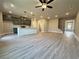 Open-concept living room with light gray floors, ceiling fan, and eat-in kitchen island with views to front door at 5702 Urban Village Way # 2, Tucker, GA 30084