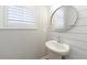 Stylish powder room with shiplap wall, a round mirror and a pedestal sink at 6645 Cortland Walk, Alpharetta, GA 30005