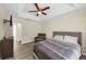 This bedroom offers a tray ceiling, ceiling fan, chair, gray wood-look flooring and a TV at 2880 Field Spring Dr, Lithonia, GA 30058