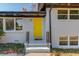 Close-up of the house with a bright yellow front door, contrasting the white brick and black trim at 2103 Columbia Dr, Decatur, GA 30032