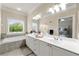 Bright bathroom featuring double sinks, a soaking tub, and a view of the verdant outdoors at 3642 Princeton Ave, Atlanta, GA 30337