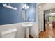 Stylish powder room featuring a pedestal sink, oval mirror, and classic blue and white wainscoting at 3642 Princeton Ave, Atlanta, GA 30337