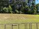 A large, grassy backyard space is pictured with an iron fence and a dense tree line at 7621 Gray Pointe Dr, Lithonia, GA 30058