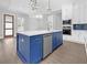 Stylish kitchen featuring a blue island, white cabinets, modern appliances, and designer lighting at 3312 Mill Forest Dr, Conyers, GA 30094
