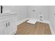 Bright laundry room with wood-look flooring, white cabinets, and modern sink fixture at 3312 Mill Forest Dr, Conyers, GA 30094