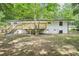 View of the home's backyard featuring a freshly-stained deck, painted brick, and level lot with mature trees at 5729 Jefferson Ave, Forest Park, GA 30297
