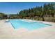 Brightly lit community pool with a zero entry point and a sundeck is surrounded by mature trees at 704 Chipping Sparrow St, Canton, GA 30115