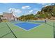 A green and blue tennis court with a black fence and green trees in the background at 704 Chipping Sparrow St, Canton, GA 30115