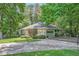 Residential home featuring a driveway leading to a garage, surrounded by a stone facade, greenery, and tall trees at 125 Fortuna Ct, Roswell, GA 30075