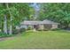 Charming single-story home featuring a well-manicured lawn and a stone facade, surrounded by mature trees at 125 Fortuna Ct, Roswell, GA 30075