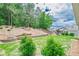 Landscaped backyard features green grass, retaining wall, and mature trees on a sunny day at 213 Hickory Bluffs Pkwy, Canton, GA 30114
