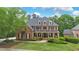 Stately brick home featuring a welcoming front porch and professionally landscaped yard with mature trees at 120 Burford Holw, Alpharetta, GA 30022