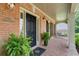 Charming front porch featuring brick flooring, a black front door, and decorative potted plants at 120 Burford Holw, Alpharetta, GA 30022