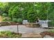 Charming patio with a stone fire pit, comfortable seating, and lush landscaping for outdoor relaxation at 120 Burford Holw, Alpharetta, GA 30022