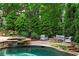 Relaxing backyard pool area features a fire pit, outdoor seating, and mature trees for privacy at 120 Burford Holw, Alpharetta, GA 30022