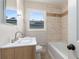 Bright bathroom featuring a tiled bathtub, a modern sink and vanity, and a window at 3890 Cherrydale Se Ln, Smyrna, GA 30082