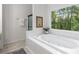Bathroom soaking tub with tile surround and leafy outdoor view at 5560 Pilgrim Point Ext, Cumming, GA 30041