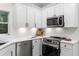 Close-up of kitchen with stainless steel appliances, white cabinets, and natural light from a window overlooking the backyard at 5560 Pilgrim Point Ext, Cumming, GA 30041