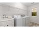 Bright laundry room featuring laundry sink, washer, dryer, and wire storage shelving at 5560 Pilgrim Point Ext, Cumming, GA 30041