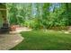 Expansive backyard featuring lush green lawn and wooded boundary, complemented by a cozy deck and gravel area at 220 Hillswick Ct, Atlanta, GA 30328
