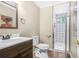 Well-lit bathroom featuring a wood vanity, toilet, and a shower with decorative tile at 220 Hillswick Ct, Atlanta, GA 30328