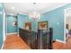 Hallway with wood floors, bright blue walls, art pieces, and crystal chandelier at 220 Hillswick Ct, Atlanta, GA 30328