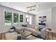 Bright living room featuring a large sectional sofa, modern lighting, and a view of lush greenery outside at 3982 Carver Cir, Doraville, GA 30360