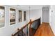 Upstairs hallway with hardwood floors, windows overlooking the front yard, and elegant iron and wood stair railing at 4649 Equestrian Way, Atlanta, GA 30338