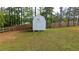 Backyard view of a white storage shed with a fenced in yard and trees at 62 Presley Farm Pkwy, Rockmart, GA 30153