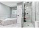 This bathroom features a walk-in shower and a tub next to a window at 2334 Fisher Dr, Loganville, GA 30052