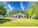 Beautiful white brick home with a well-kept lawn, surrounded by lush trees and an American flag at 2334 Fisher Dr, Loganville, GA 30052