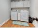 Bright laundry room featuring washer, dryer, storage cabinets and wood-look flooring at 2334 Fisher Dr, Loganville, GA 30052