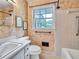 Bathroom featuring a tub and shower, with support bars, tiled surround, and a window at 3089 Ranlo Dr, Atlanta, GA 30340