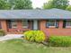 Close up of a charming red brick home with lush green landscaping and mature shrubbery at 3089 Ranlo Dr, Atlanta, GA 30340