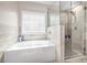 Bright bathroom featuring a tiled tub and a glass-enclosed shower at 5652 Burruss Rd, Cumming, GA 30028