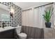 Well-lit bathroom features an updated vanity, toilet, patterned wallpaper, and tiled shower with curtain at 2647 Forrest Nw Ave, Atlanta, GA 30318